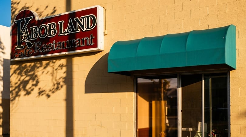 The exterior of Kabob Land Cafe & Restaurant with a red sign and a green awning.